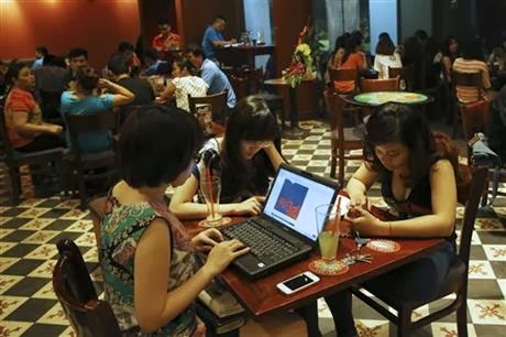 Trong bức ảnh ngày 14.5.2013 này, ba cô gái Việt Nam sử dụng laptop và điện thoại thông minh để lên mạng tại một quán cà phê ở Hà Nội. Các nhà hoạt động dân chủ và blogger Việt Nam đang chiến đấu chống lại một chiến dịch ngăn chặn, hack và do thám mà một đội quân bí mật ủng hộ chính phủ tiến hành trên mạng. Mặc dù họ không thể chứng minh được điều đó, song các nhà hoạt động và chuyên gia phân tích rất nghi ngờ sự dính líu của chính phủ Việt Nam trong chiến dịch, vốn đang kìm hãm phong trào dân chủ ở đất nước này. Ảnh: (AP Photo/Na Son Nguyen, File)
