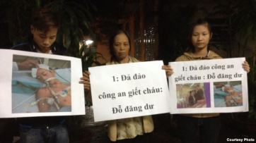 Mẹ và anh chị của nạn nhân Đỗ Đăng Dư cầm biểu ngữ phản đối. (Facebook: Dung Truong)