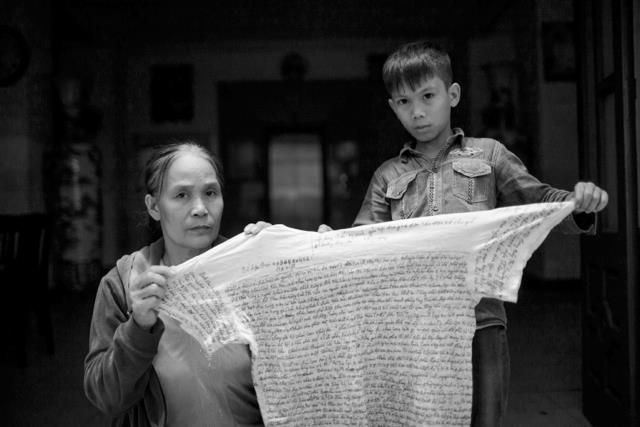 Bà Việt và cháu Kiên, con của anh Mạnh cầm thư viết trên áo của anh Mạnh gửi ra. Nguồn: FB Chau Doan