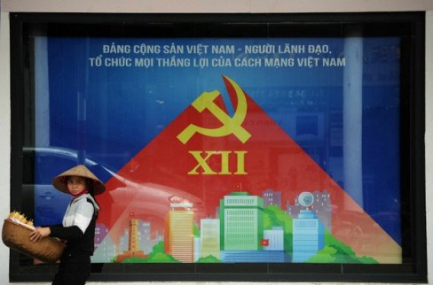 Một người bán hàng rong đi qua một tấm áp phích tuyên truyền cho Đại hội toàn quốc Đảng Cộng sản Việt Nam trên đường phố Hà Nội ngày 15 tháng 1 năm 2016. AFP Photo