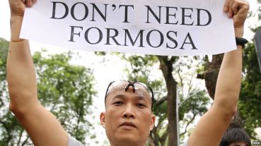 Người biểu tình cầm biểu ngữ phản đối công ty Formosa gây ô nhiễm dẫn tới vụ cá chết ở Hà Tĩnh. Ảnh: EPA