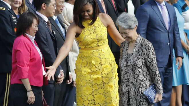 Bà Ho Chung (phải), tay cầm cái ví trị giá $11. Người mặc đầm vàng là Đệ nhất Phu nhân Michelle Obama