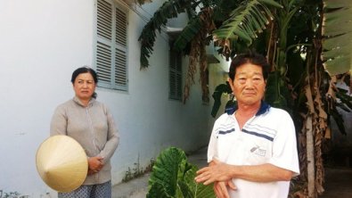 Vợ chồng ông Thương đứng bên dãy nhà mà ông Việt xây lấn để cho thuê. (Hình: Báo Tiền Phong)